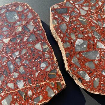 Close up view of two cross sections of a reddish brown material with embedded gray and white angular fragments showcasing a natural geological texture photo