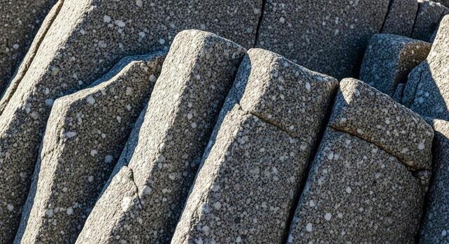Close up view of weathered grey granite rock formations with sharp angular edges and a speckled texture under bright sunlight photo