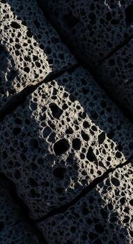 Close up textured abstract pattern of porous material with dramatic light and shadow play creating depth and intrigue photo