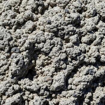 cerca arriba ver de un texturizado superficie compuesto de pequeño irregular y poroso agregar materiales en variar sombras de gris y bronceado foto