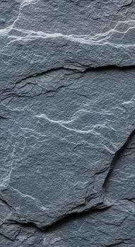 Close up abstract texture of dark grey slate stone with natural layered patterns and subtle light and shadow variations photo