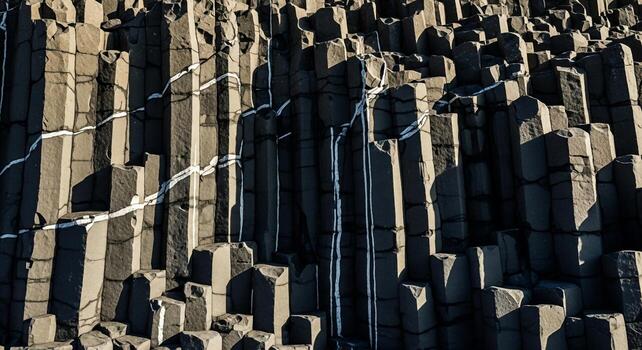 Close up view of naturally formed hexagonal basalt columns creating a textured geological pattern in sunlight photo