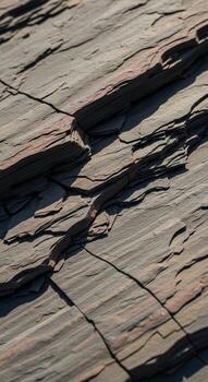Close up abstract view of weathered slate rock with distinct horizontal striations and deep shadows creating a textured natural surface pattern photo