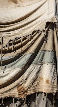 Close up view of a weathered and torn camouflage tarp with frayed edges and visible stitching details photo
