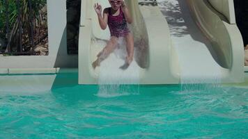 jung Kind im Badeanzug und Brille Folien Nieder in ein Schwimmen Schwimmbad Herstellung ein groß Spritzen auf ein sonnig Tag video