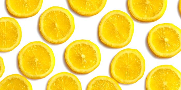 Bright yellow lemon slices are scattered on a clean white background creating a fresh and vibrant pattern photo