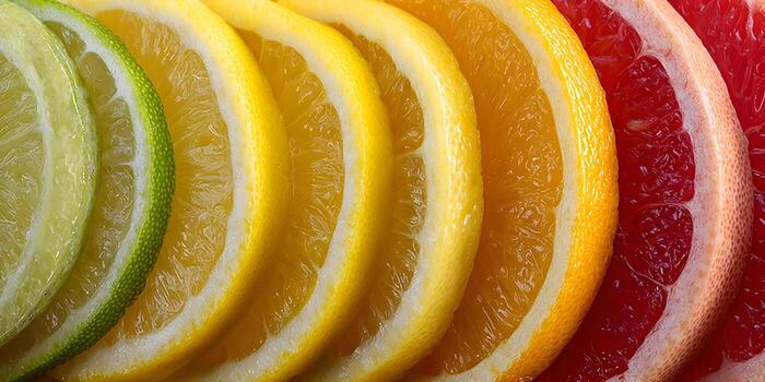 A vibrant close up of colorful citrus fruit slices arranged in a gradient including lime lemon orange and grapefruit photo