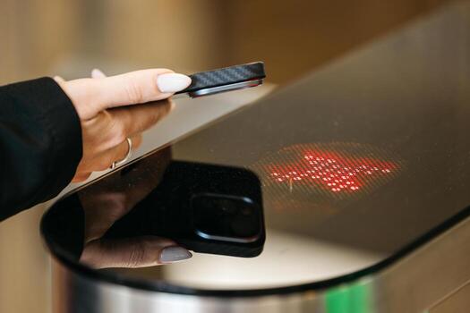 Female user with smartphone tapping on modern access control system, illuminated by red light, showcasing technology interaction and security features in a contemporary environment photo