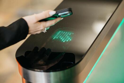 Hand of a woman using smartphone to interact with a modern biometric scanner, showcasing advanced technology and security features in a sleek environment with illuminated design elements photo
