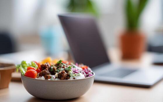 Warm lunch bowl sits on modern workspace next to laptop inviting a break and enjoyment during work hours photo