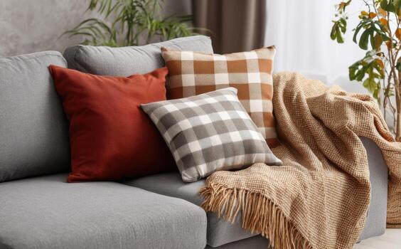 Cozy autumn plaid pillows and blanket create a warm atmosphere on a grey sofa photo