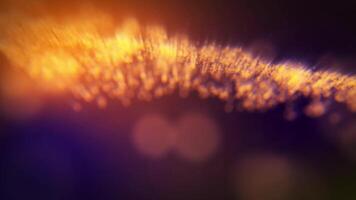 A mesmerizing flow of shimmering golden particles creating a luminous wave of energy on an abstract, dark, and blurred background with bokeh video