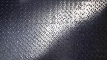 A metal surface with a repeating raised diamond pattern and light reflecting across it evenly textures patterns background video
