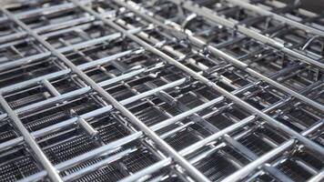 A close up view of a shiny metal grid pattern with intersecting lines and rectangular openings shown textures patterns background video