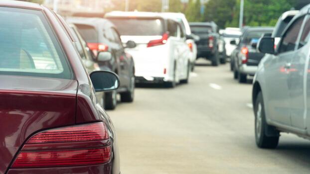 Rear side of red color parked in a line in a curve on the concrete road. With traffic congestion. Blurred of trees for background. photo