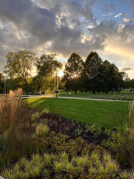 Park with Pathway, Trees, and Playground Under Partly Cloudy Sky photo