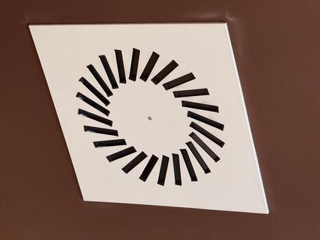 Circular vent grille in modern ceiling interior. Visual exploration of geometry, function, and engineered precision in minimal architectural composition. photo