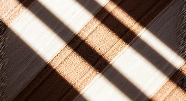 Warm sunlight creating diagonal shadow patterns on a textured plaid surface. photo