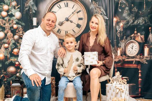 Smiling mother holds a wrapped present while father and son join in the festive scene photo