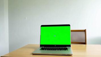 portable avec Vide vert écran sur une tableau. intérieur de vivant chambre. ordinateur moniteur vert Contexte maquette. numérique chrominance clé afficher. moderne PC modèle. travail de Accueil concept. suivi coup video