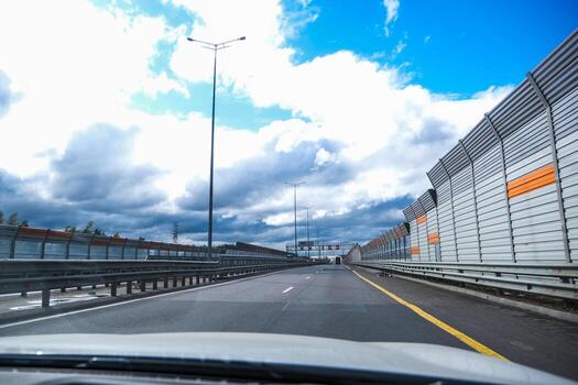 Empty highway view from car dashboard on a cloudy day with sound barrier. Perspective car drive on road infrastructure. photo