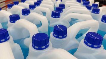 Plastic detergent bottles with blue caps, viewed from above, creating a repeating pattern video