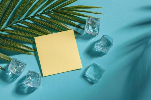 Blank note card, ice cubes and palm leaves on blue background photo