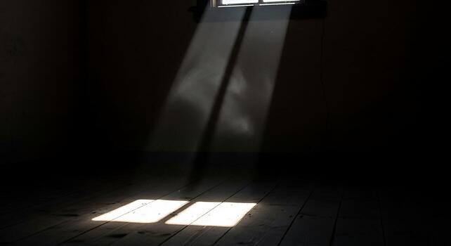 Sunlight Streaming Through a Small Window Creating Shadow Patterns on Dark Floor photo