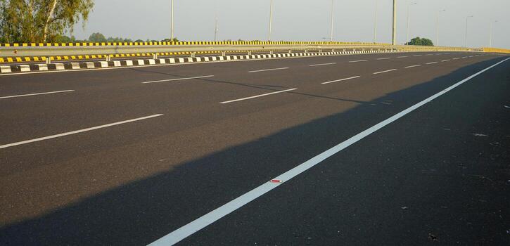 Low Angle View of Empty Modern Highway with Safety Barrier and Road Lines photo
