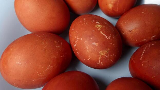 Several textured red and brown Easter eggs neatly arranged on soft blue plate photo