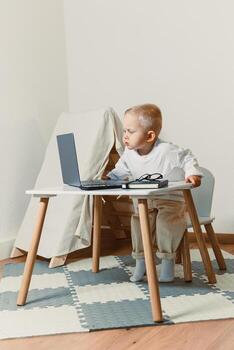 A curious toddler is joyfully engaged in computer play, sitting at a stylish study table in a contemporary room setting that enhances their learning experience and fosters imagination and exploration photo
