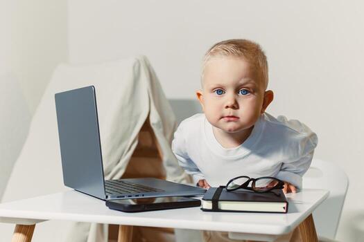 A Curious Baby Enthusiastically Exploring Technology A Young Child Fully Engaged with a Laptop and Notepad in a Clean and Minimalist Workspace Environment, Eager to Learn and Discover, with Joy photo