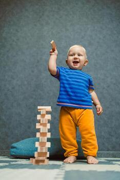 un alegre niñito felizmente atractivo en jugar con brillante y vistoso de madera bloques en un acogedor interior configuración, lleno con creatividad y imaginación, alentador aprendizaje y desarrollo mediante jugar foto