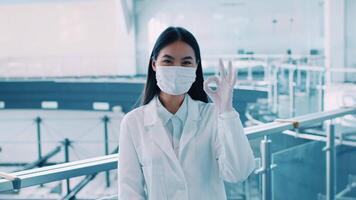 uma mulher dentro uma laboratório casaco e mascarar mostra uma positivo gesto enquanto trabalhando dentro uma pesquisa laboratório. dela arredores estão alta tecnologia, refletindo uma focado e Inovativa local de trabalho atmosfera. video
