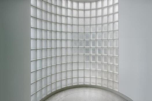 Curved Glass Wall in an Indoor Setting Featuring Grid Design with Natural Light Flowing Through the Transparent Blocks Creating a Modern Architectural Look photo