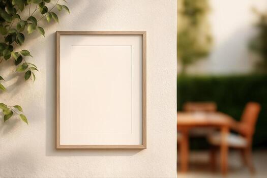 Outdoor Patio With Empty Picture Frame On Wall Next To Greenery And Garden Furniture Blurred In The Background On A Sunny Day photo
