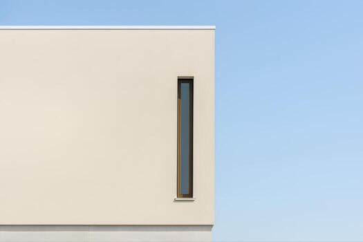Modern Minimalist Facade On A Stucco Building Against A Clear Blue Sky In Broad Daylight Featuring A Thin Vertical Window photo