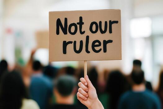 Not Our Ruler Protest Rally Featuring a Placard Held Up by a Participant with a Crowd in the Background and a Message Displaying Political Dissent photo