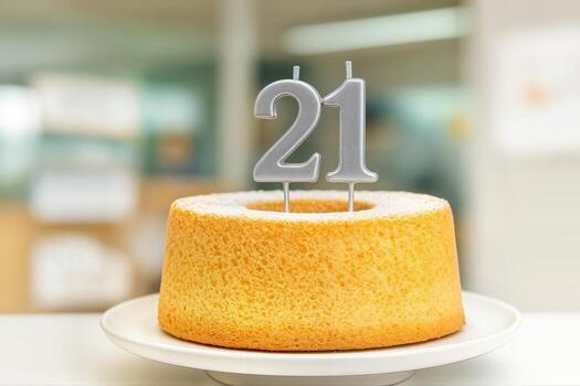 21st Birthday Cake Indoor on White Plate with Silver Candle Numbers in Focus in a Bright Kitchen Setting With Shallow Depth Of Field photo