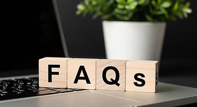 Wooden blocks spelling FAQs resting on a laptop keyboard in a modern office setting symbolizing information access and customer support with a focus on clarity and helpfulness for online users photo