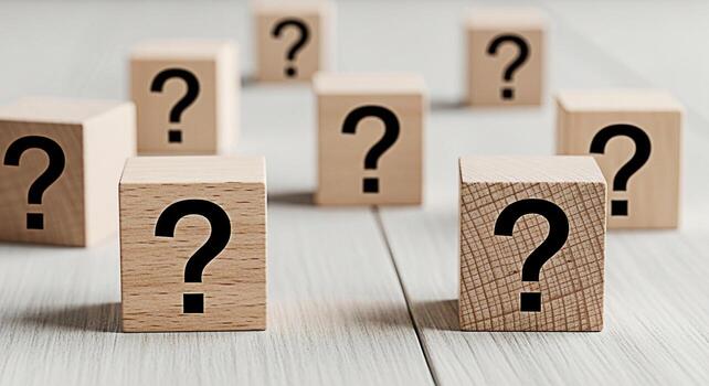 Wooden blocks displaying question marks on a textured white surface representing uncertainty and the search for answers in a conceptual and minimalist composition evoking curiosity and problemsolving photo