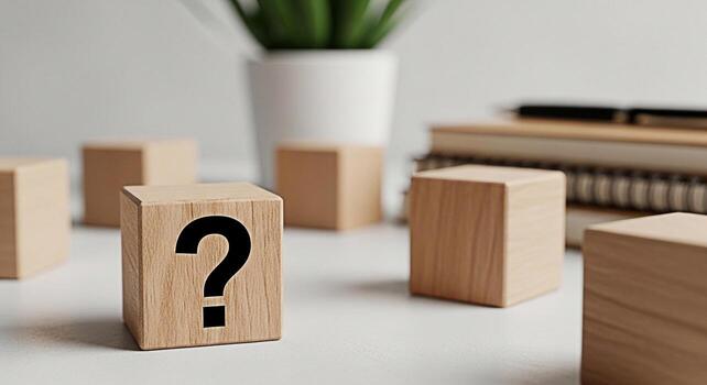 Wooden cube displaying a question mark on a bright white desk with books and a plant representing curiosity problemsolving and the search for answers in a clean and modern environment photo