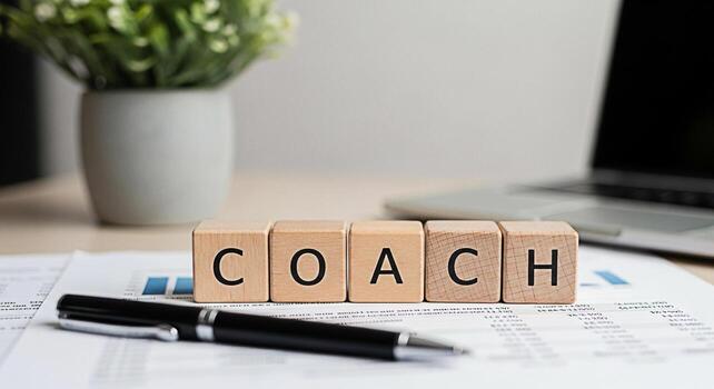 Wooden blocks spelling COACH on a desk with financial reports and a pen symbolizing business guidance and mentorship in a professional setting fostering a supportive and growthoriented environment photo