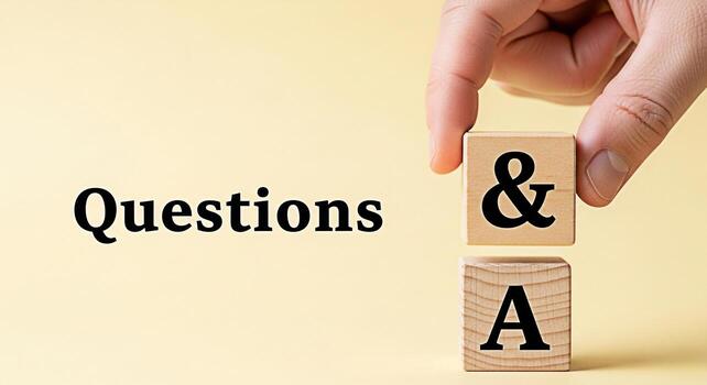 Hand arranging wooden blocks with symbol on top of A block next to the word Questions on a yellow background representing a question and answer session knowledge and information photo