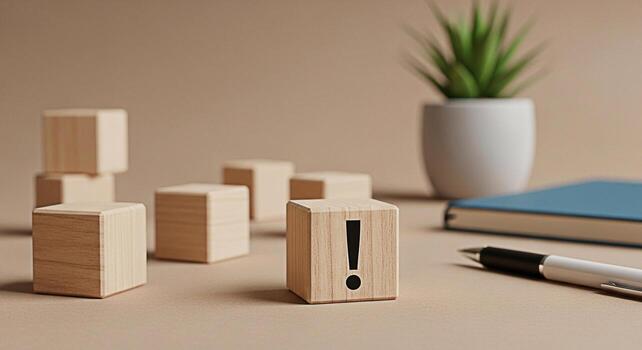 Wooden block displaying an exclamation mark on a desk symbolizing attention and importance in a calm minimalist workspace with a notebook pen and plant creating a focused and organized atmosphere photo