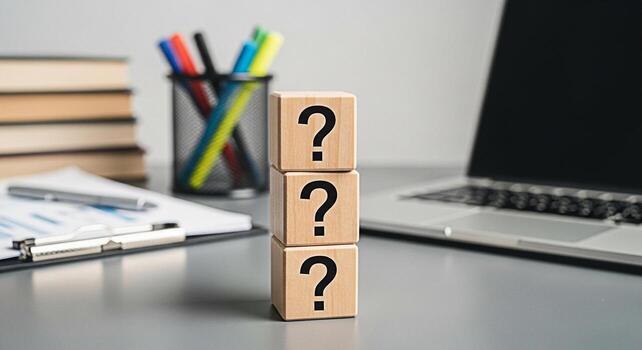 Wooden blocks displaying question marks on a modern office desk with laptop and documents representing uncertainty problemsolving and the need for answers in a professional environment photo