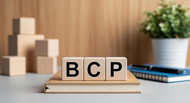 Wooden blocks displaying BCP resting on a book in a bright office setting symbolizing Business Continuity Planning and resilience in the face of challenges for strategic business management and growth photo
