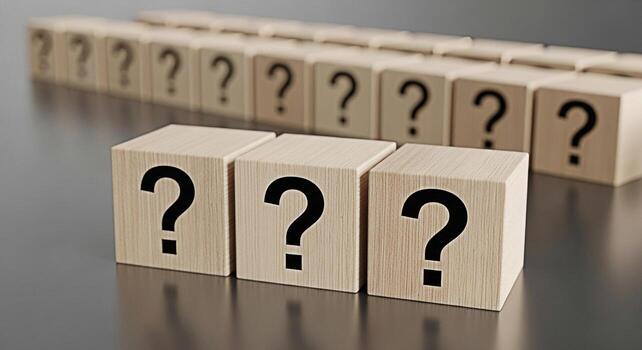 A row of wooden blocks displaying question marks symbolizing uncertainty and inquiry in a neutral setting evoking a sense of mystery and the search for answers photo