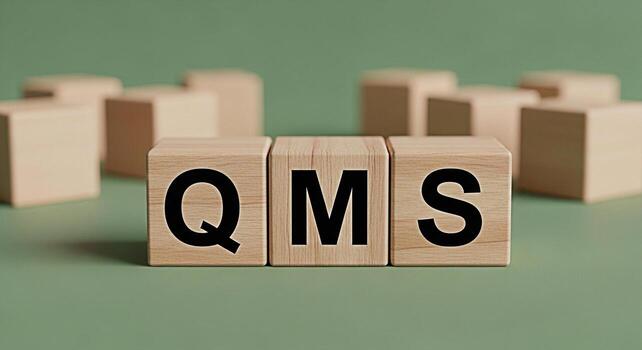 Wooden blocks displaying QMS on a green surface representing quality management system in a business environment conveying a sense of organization efficiency and adherence to standards photo