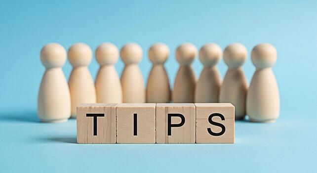 Wooden figures standing behind wooden blocks displaying the word TIPS on a light blue background representing advice guidance and helpful information for success and problemsolving photo